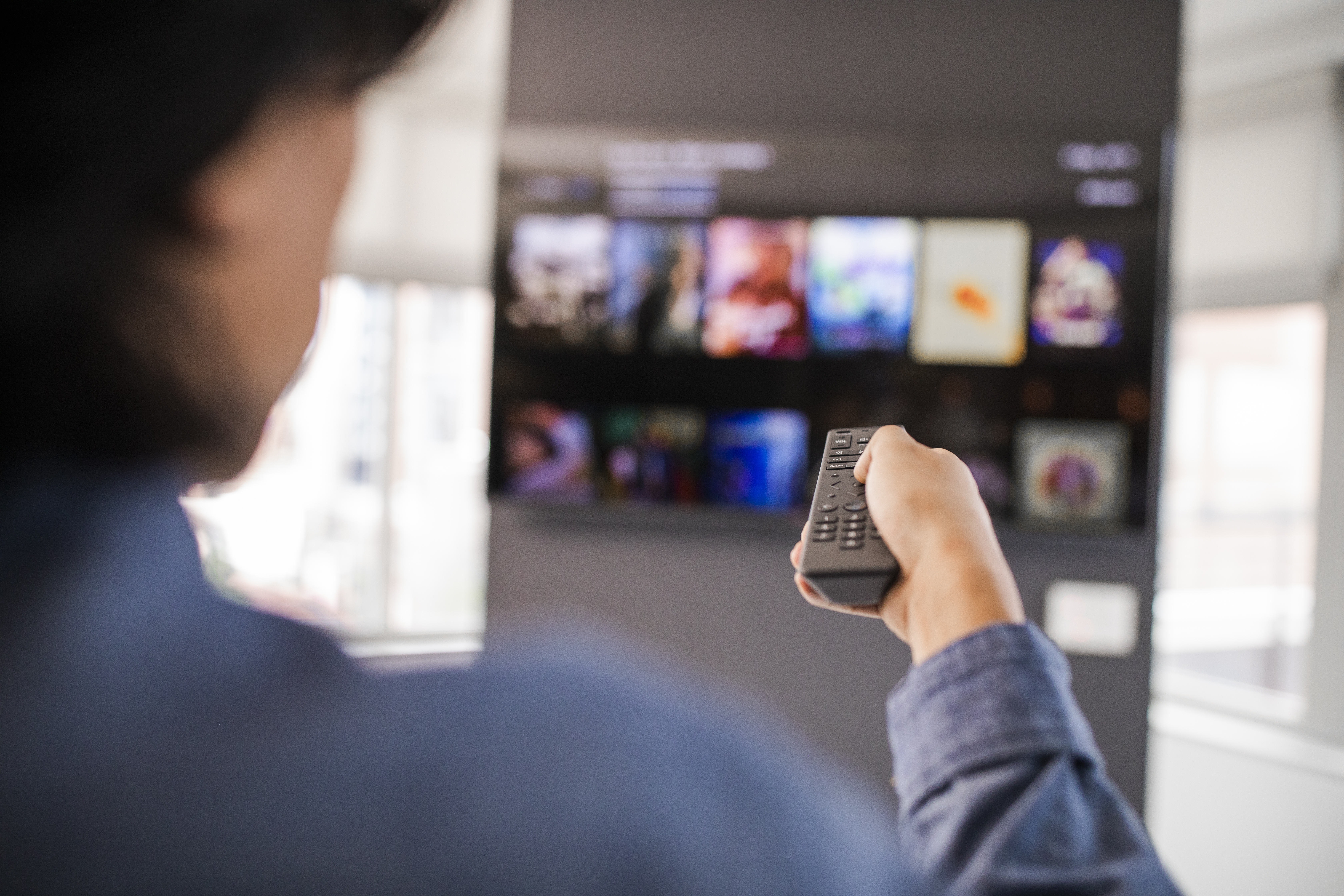 man pointing remote at tv