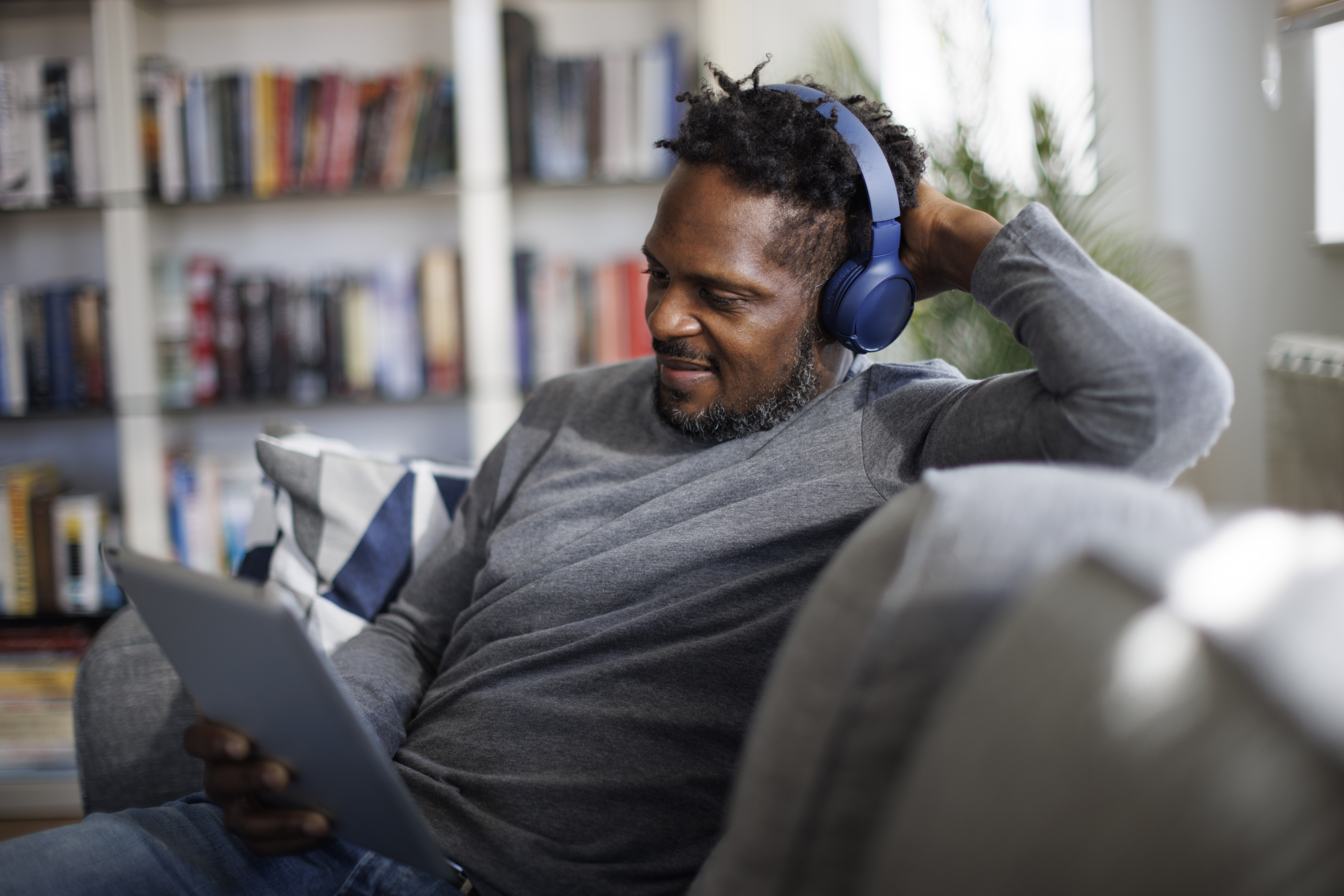 Person listening to audio content on a tablet through headphones.