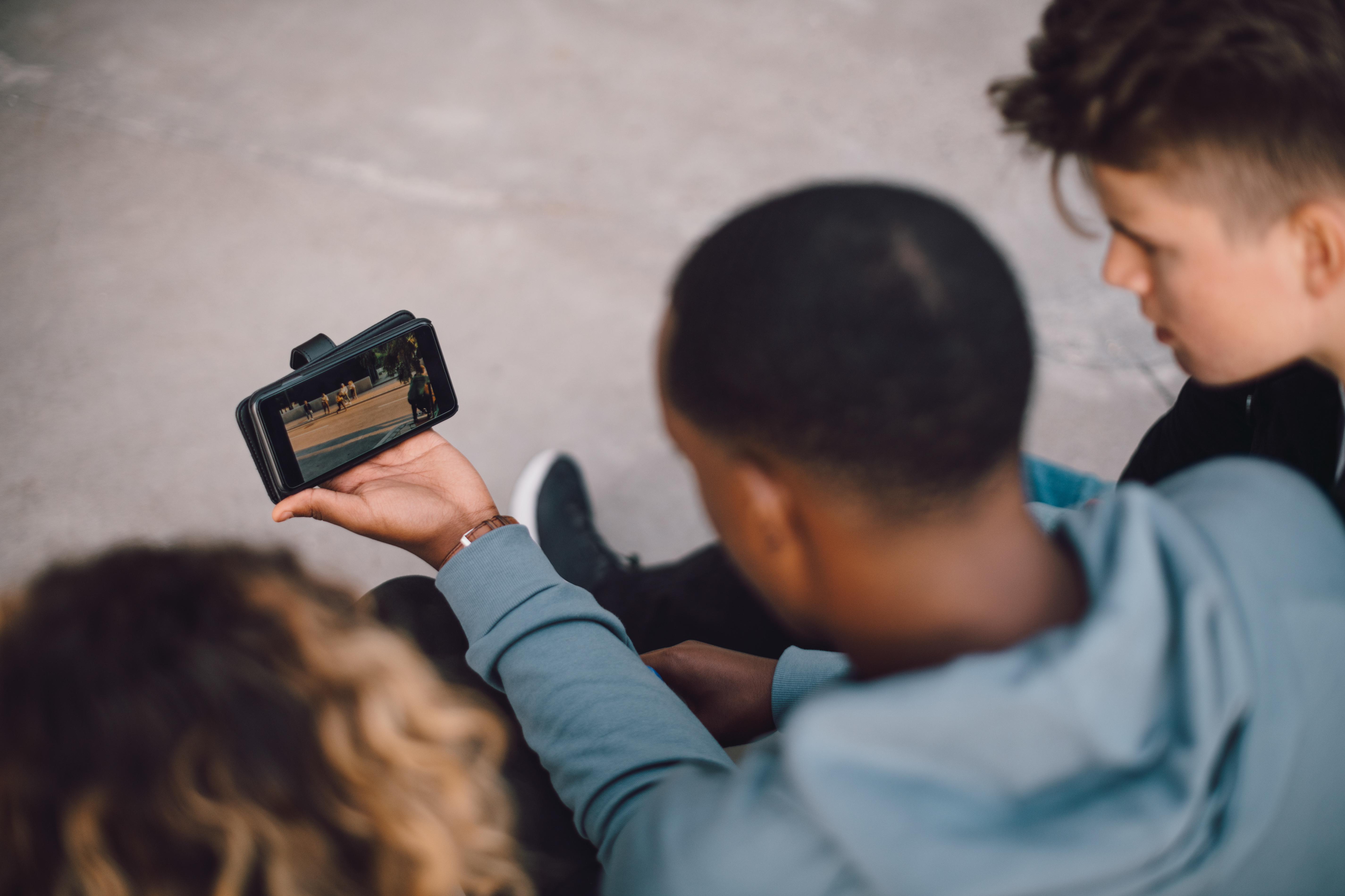 three people looking at a phone in a sports venue watching sports highlights