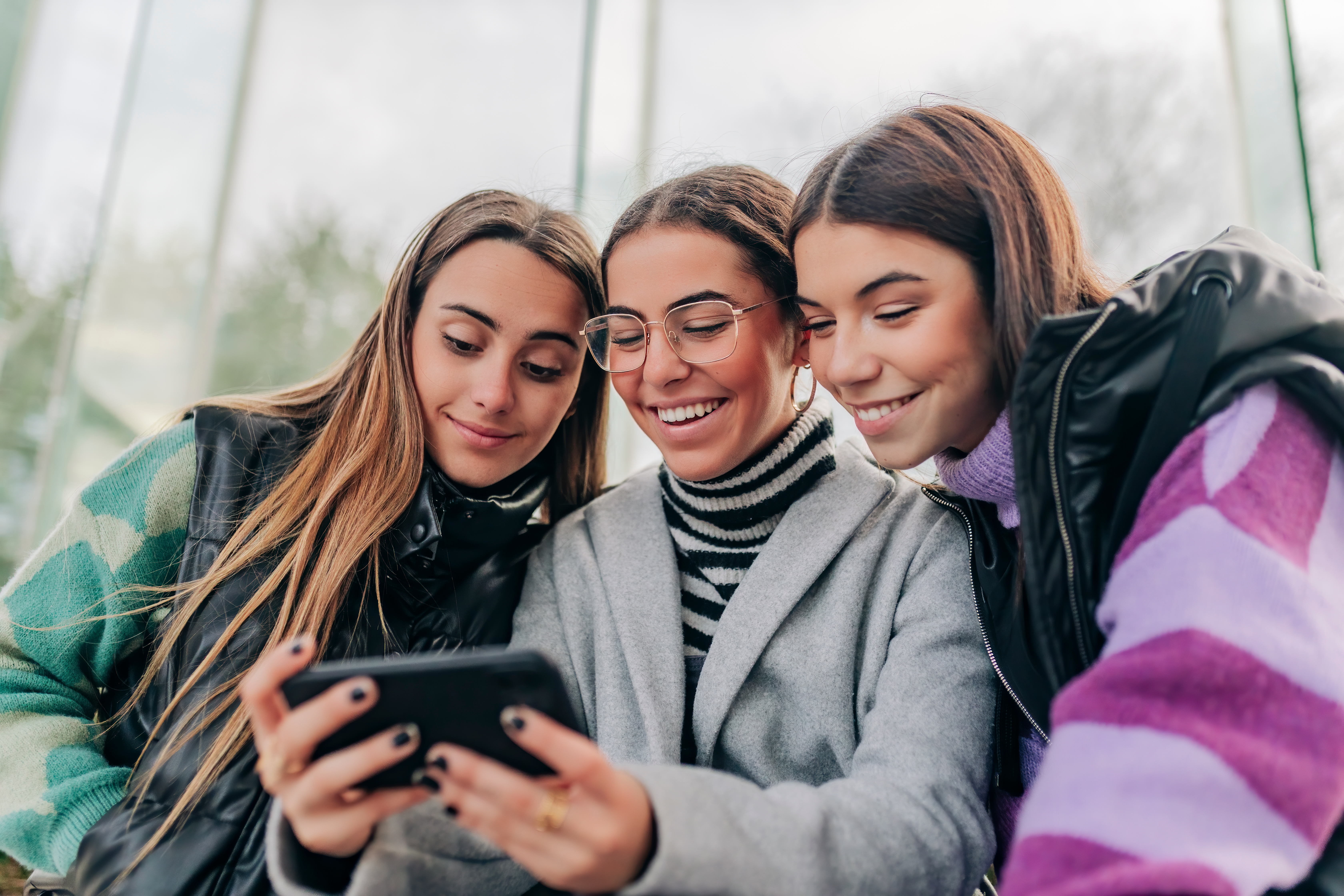 three people looking at one phone watching sports highlights