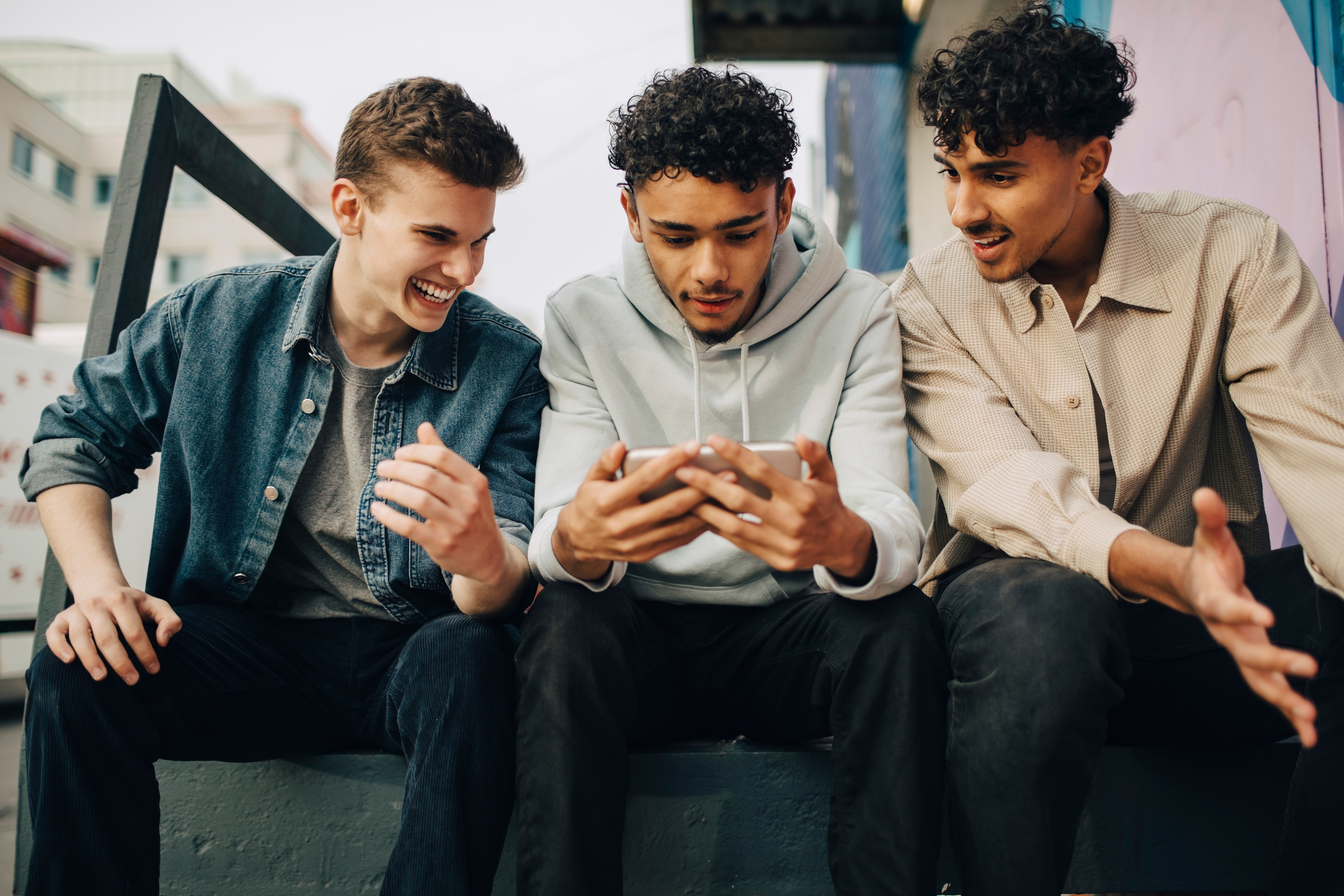 three people watching sports a phone