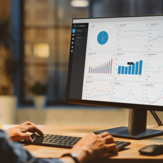 person working on desktop with graphs on the screen