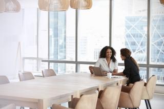 business women chatting at a table with a laptop between them