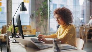 woman looking at a computer screen, typing on a keyboard