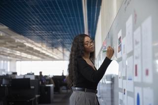 person writing on whiteboard wall in office