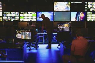 technology man points at control room screens