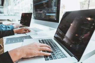 two sets of hands working on laptops