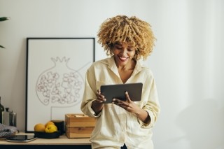 a woman smiling while looking at a tablet