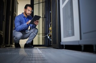 man in a server room holding a tablet