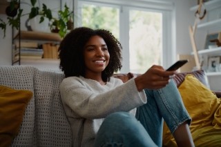 a woman on a couch holding a television remote