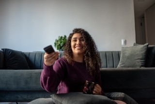 woman in a purple sweatshirt holding a remote for a television