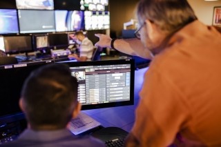 man points at control room screens