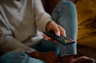 womans hand holding a remote control