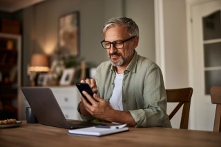 man working on a laptop with a phone in his hands