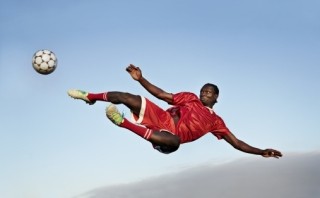 man in air kicking a soccer ball