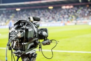 Broadcast camera positioned beside a sports field during a live event