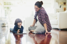 child on tablet sitting next to mom figure