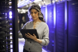 Woman on tablet standing in room of servers