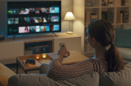 a woman watching tv and holding the tv remote pointed at the tv