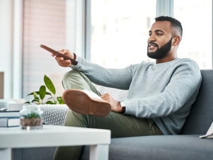 man on couch holding remote