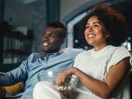 Couple watching television on a couch with popcorn