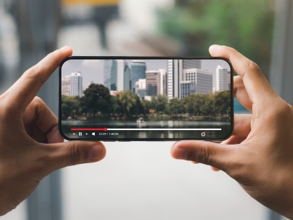 Hands holding a smartphone displaying a video