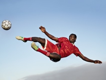 man in air kicking a soccer ball