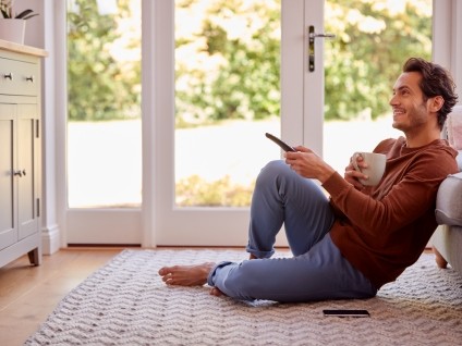 man watching tv pointing a remote at the tv and sitting on the floor
